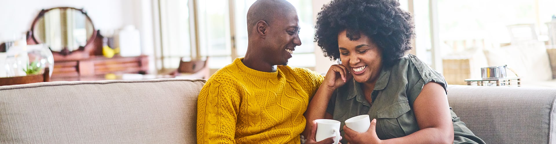 Smiling couple with coffee on couch